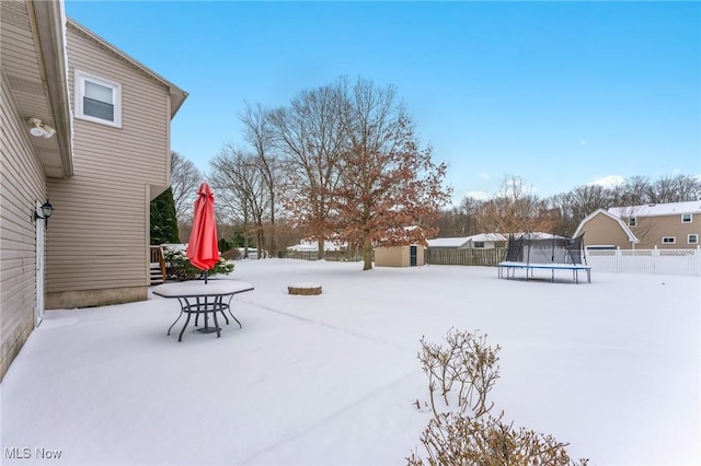 snowy yard featuring a trampoline