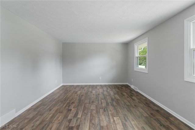 empty room with a textured ceiling and dark wood-type flooring