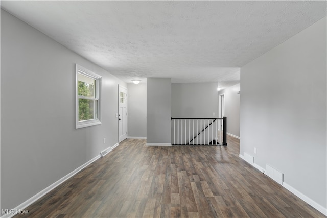 spare room with a textured ceiling and dark wood-type flooring