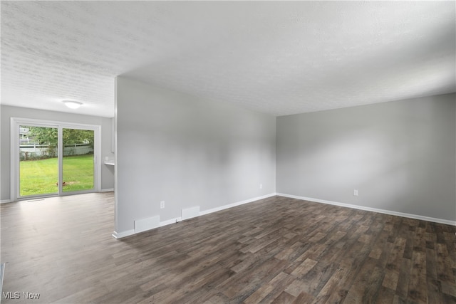 spare room with a textured ceiling and dark hardwood / wood-style floors