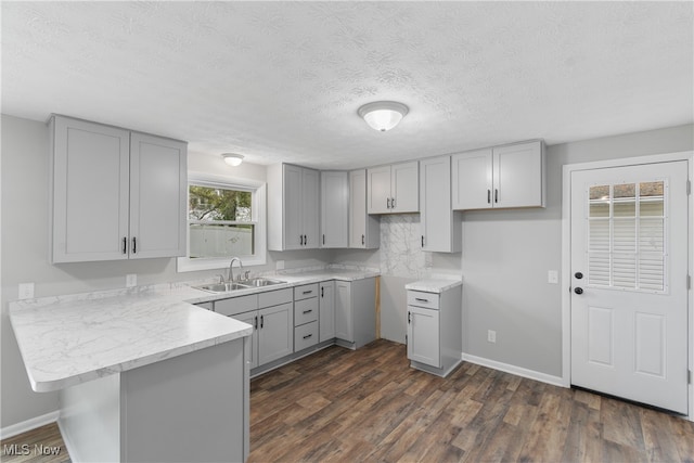 kitchen featuring dark hardwood / wood-style floors, gray cabinetry, kitchen peninsula, and sink