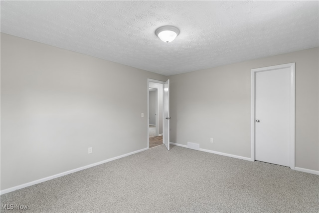 carpeted spare room with a textured ceiling