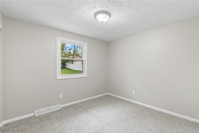 empty room with carpet floors and a textured ceiling