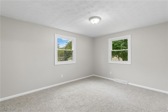 carpeted empty room with a textured ceiling