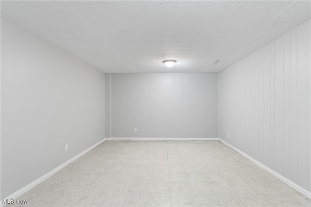 spare room featuring a textured ceiling and wood walls