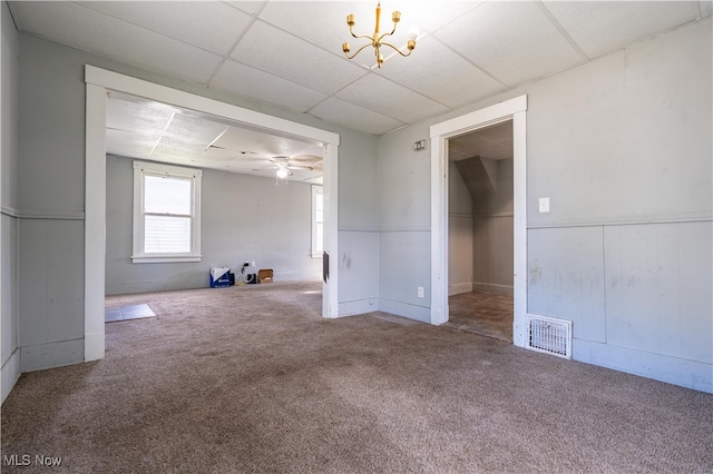 carpeted spare room with ceiling fan with notable chandelier and a paneled ceiling