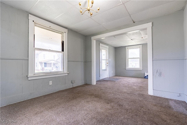 unfurnished room featuring carpet flooring, a paneled ceiling, and an inviting chandelier