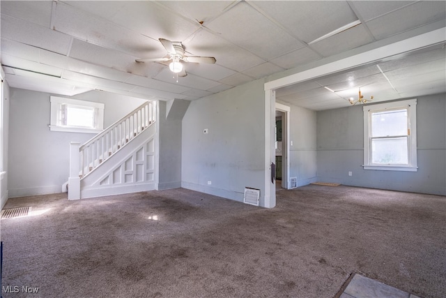 interior space featuring a drop ceiling, ceiling fan, a healthy amount of sunlight, and carpet flooring