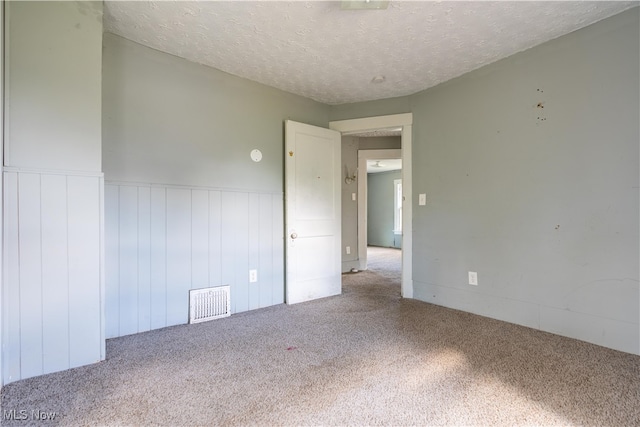 carpeted empty room with a textured ceiling