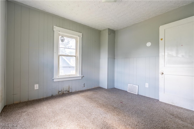 carpeted empty room featuring a textured ceiling