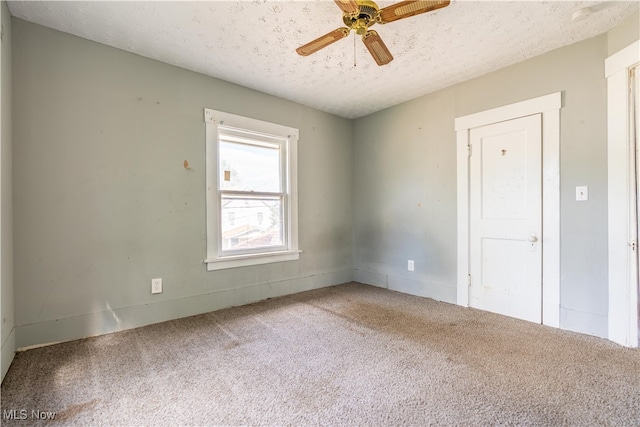 carpeted empty room featuring ceiling fan and a textured ceiling