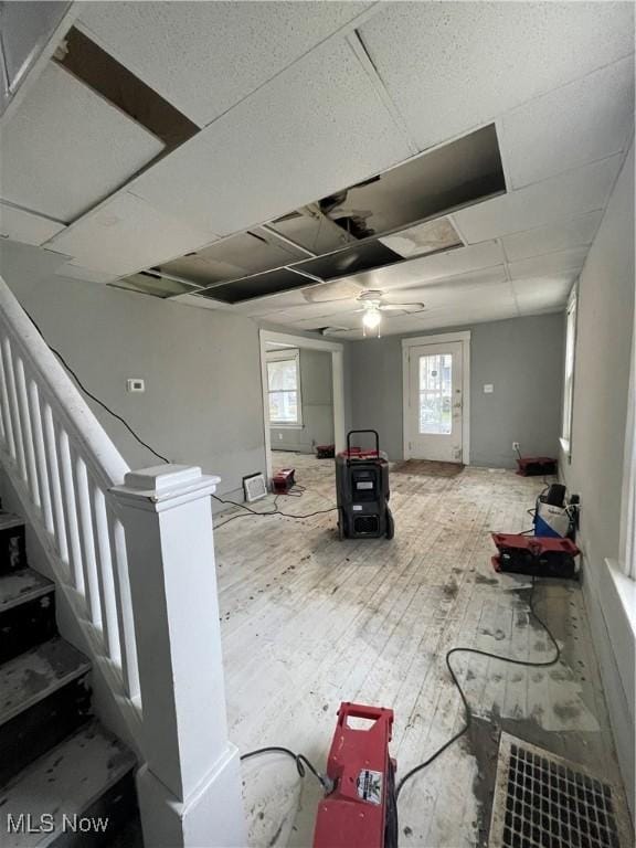 basement with ceiling fan, wood-type flooring, a healthy amount of sunlight, and a paneled ceiling