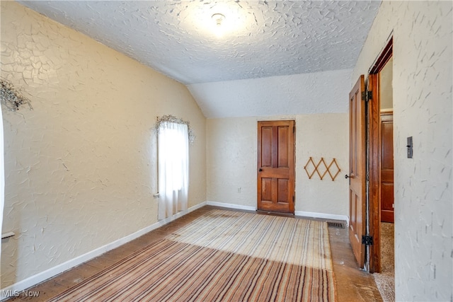 interior space with a textured ceiling and vaulted ceiling