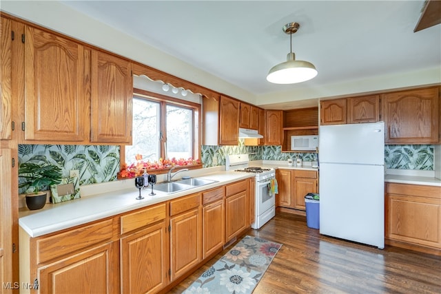 kitchen featuring decorative backsplash, white appliances, sink, decorative light fixtures, and dark hardwood / wood-style floors