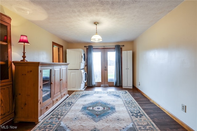 interior space with dark hardwood / wood-style flooring, stacked washing maching and dryer, a textured ceiling, and french doors