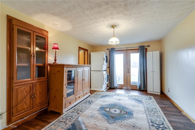 unfurnished living room featuring french doors, dark hardwood / wood-style flooring, a textured ceiling, and stacked washer / dryer