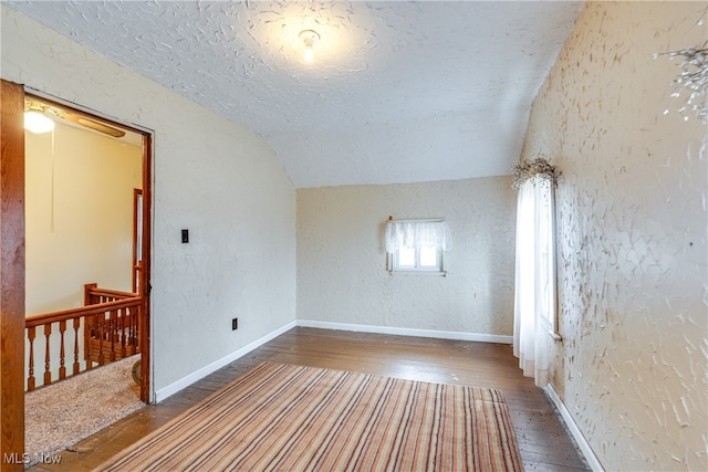 spare room with dark hardwood / wood-style floors and vaulted ceiling