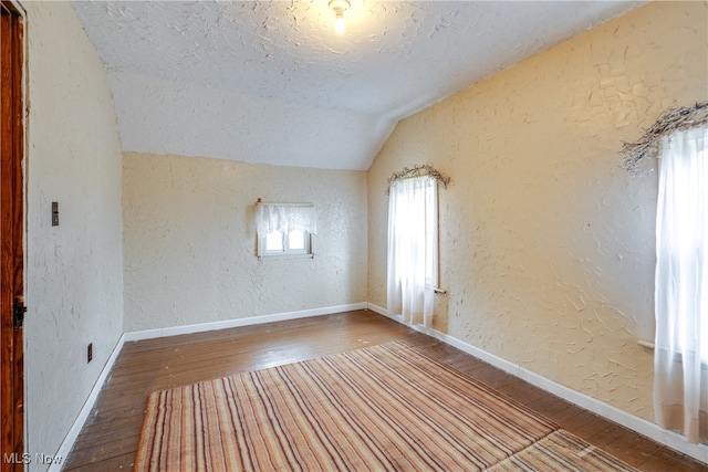 empty room with wood-type flooring and lofted ceiling