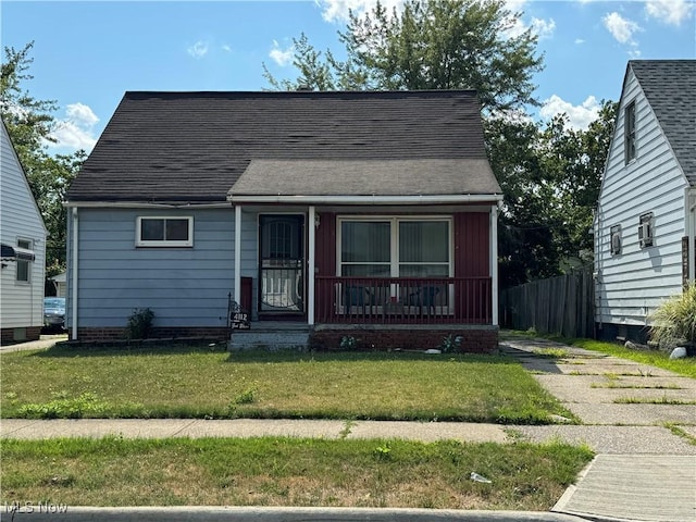 view of front of property featuring roof with shingles, covered porch, and a front lawn