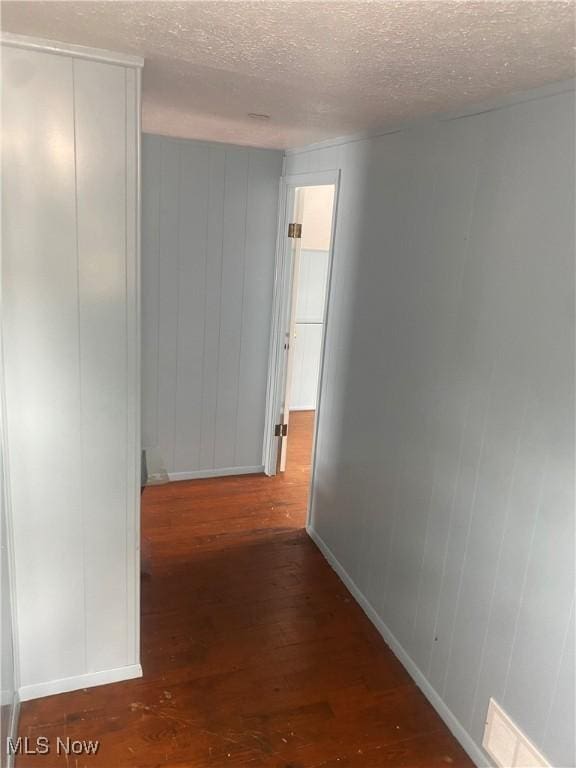 hall with baseboards, a textured ceiling, and wood finished floors