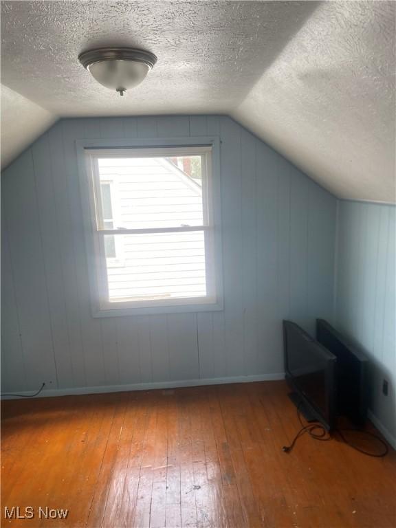 bonus room with a textured ceiling, vaulted ceiling, and hardwood / wood-style flooring