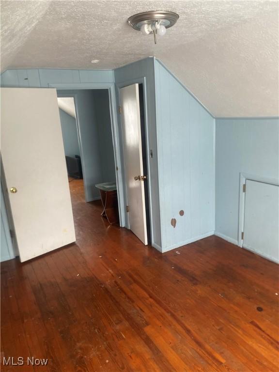 bonus room with a textured ceiling, vaulted ceiling, and hardwood / wood-style floors