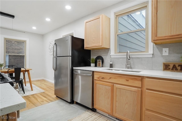 kitchen featuring tasteful backsplash, light brown cabinetry, sink, stainless steel dishwasher, and light hardwood / wood-style flooring