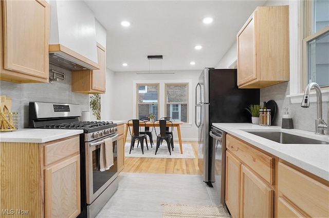 kitchen featuring custom exhaust hood, light brown cabinetry, light wood-type flooring, sink, and stainless steel appliances