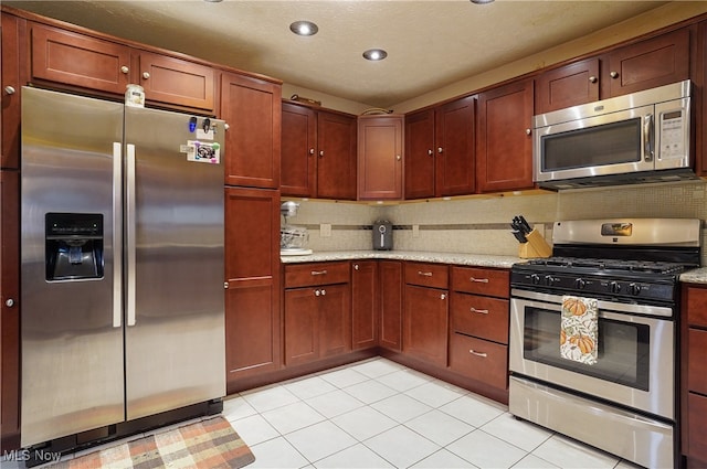 kitchen with light stone countertops, stainless steel appliances, decorative backsplash, and light tile patterned flooring