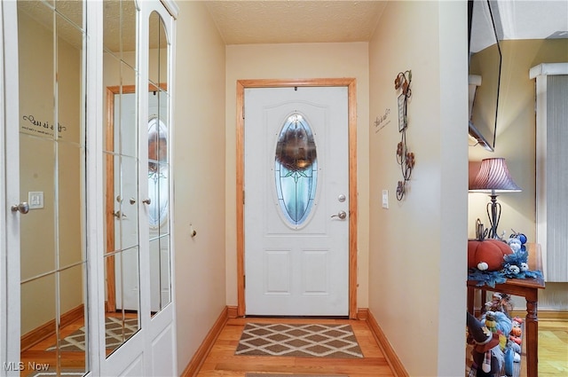 doorway to outside with light hardwood / wood-style floors and a textured ceiling