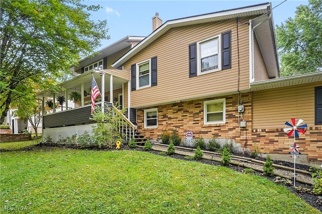 rear view of house featuring a yard and a porch