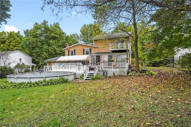 rear view of property featuring a wooden deck and a lawn