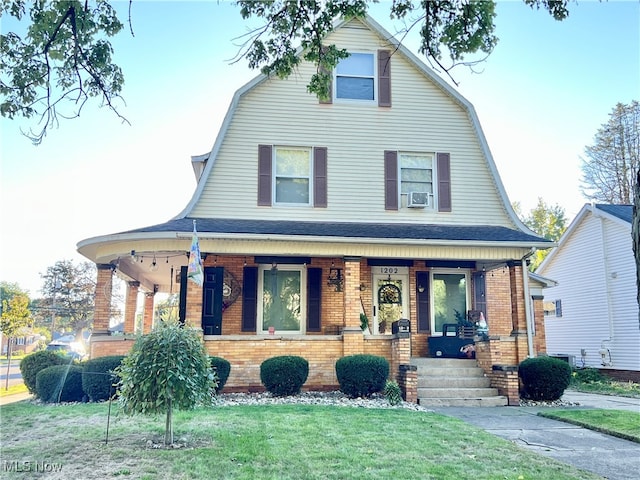 view of front facade with a front lawn, cooling unit, and covered porch