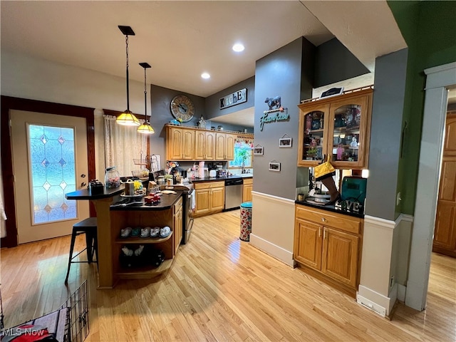 kitchen featuring sink, decorative light fixtures, light hardwood / wood-style flooring, appliances with stainless steel finishes, and a kitchen breakfast bar