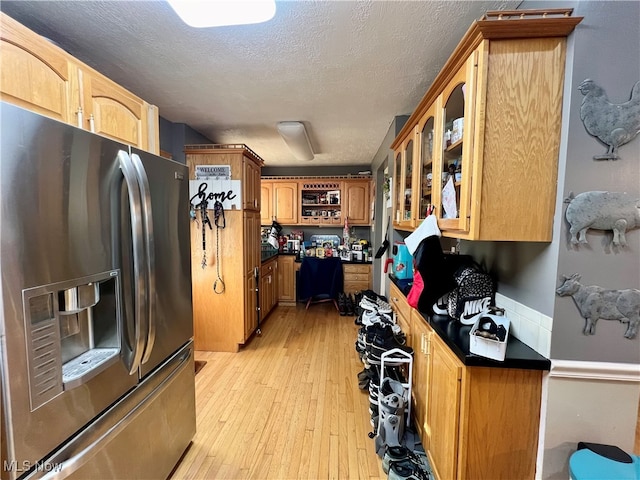 kitchen featuring light wood-type flooring, stainless steel refrigerator with ice dispenser, and a textured ceiling