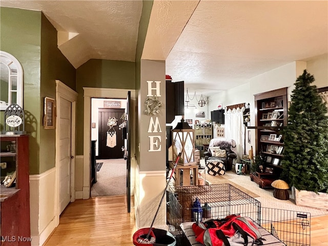 dining room featuring a textured ceiling, lofted ceiling, and light hardwood / wood-style flooring