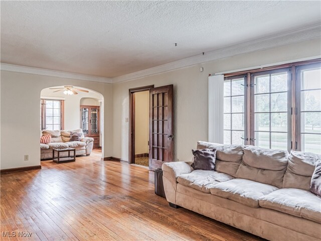 living room featuring a textured ceiling, light hardwood / wood-style floors, ceiling fan, and crown molding