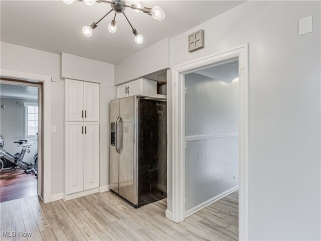 kitchen featuring an inviting chandelier, light wood-type flooring, stainless steel refrigerator with ice dispenser, and white cabinetry