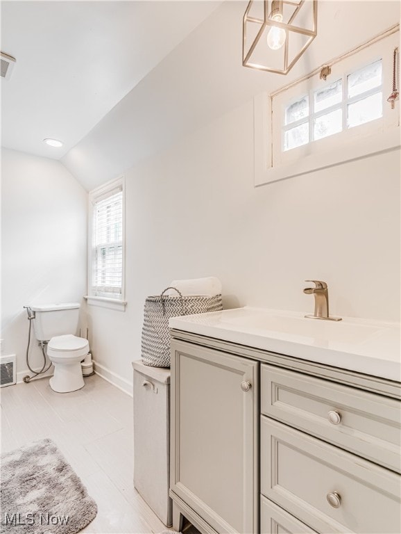 bathroom featuring tile patterned flooring, lofted ceiling, vanity, and toilet