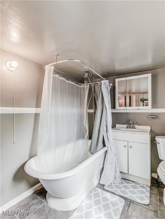 full bathroom featuring tile patterned flooring, vanity, toilet, and shower / bath combo with shower curtain