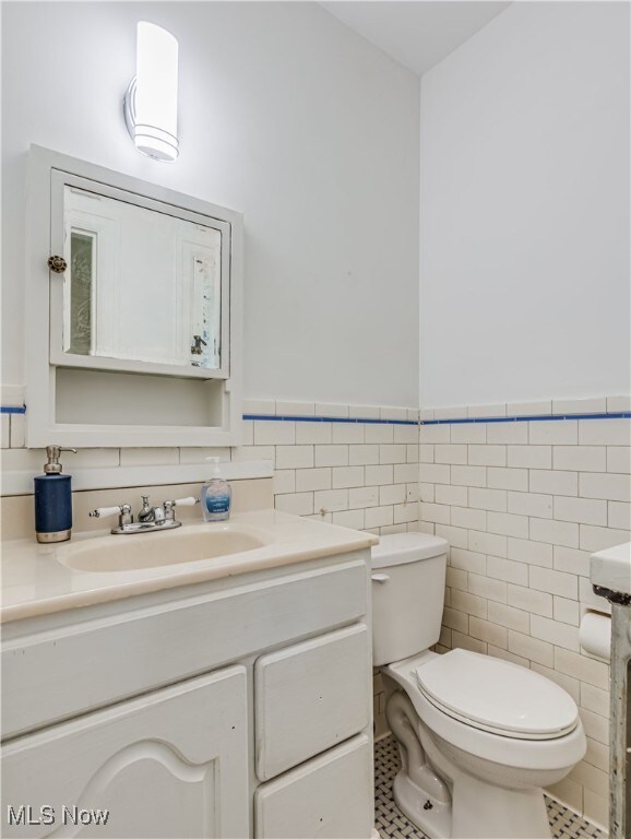 bathroom featuring vanity, tile walls, tile patterned flooring, and toilet