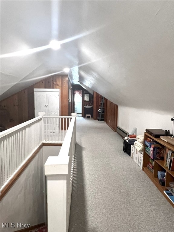 bonus room with carpet, lofted ceiling, a baseboard radiator, and wood walls