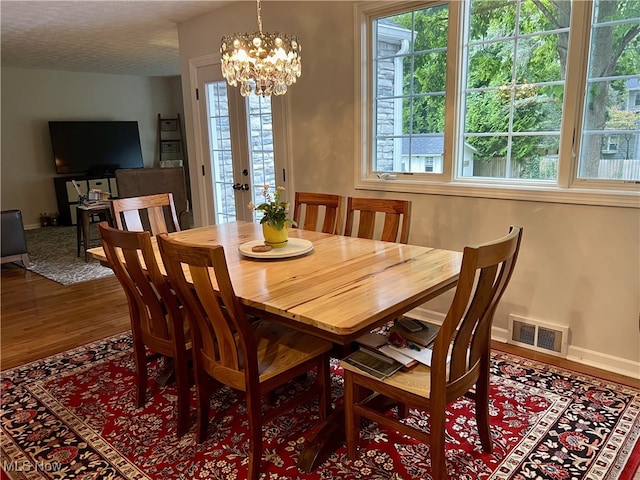 dining space with a chandelier, a textured ceiling, and hardwood / wood-style floors