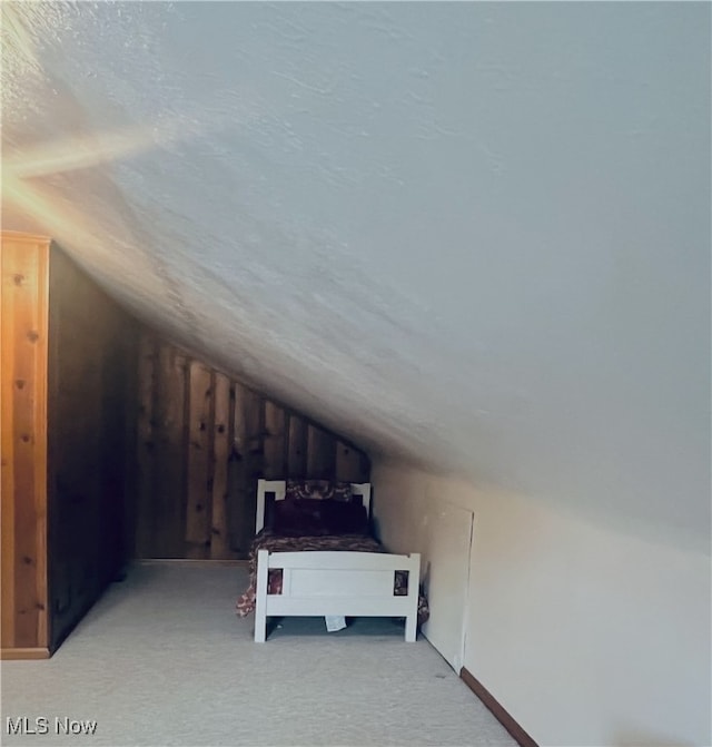 bonus room featuring a textured ceiling, vaulted ceiling, and light carpet