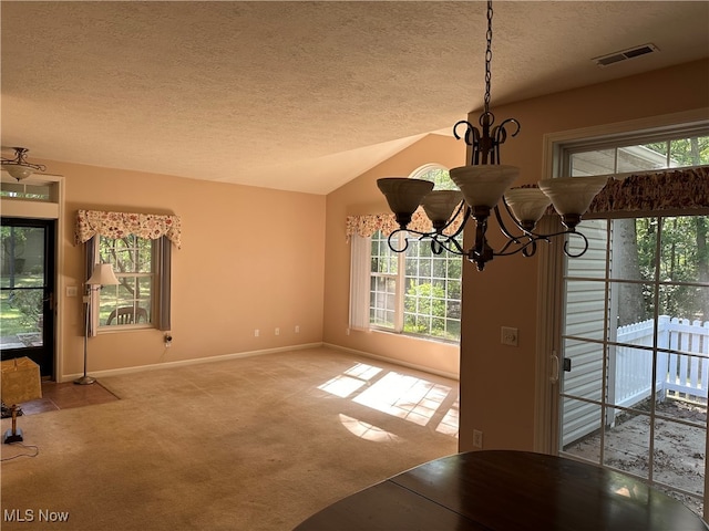 unfurnished dining area with light carpet, vaulted ceiling, a textured ceiling, and a chandelier