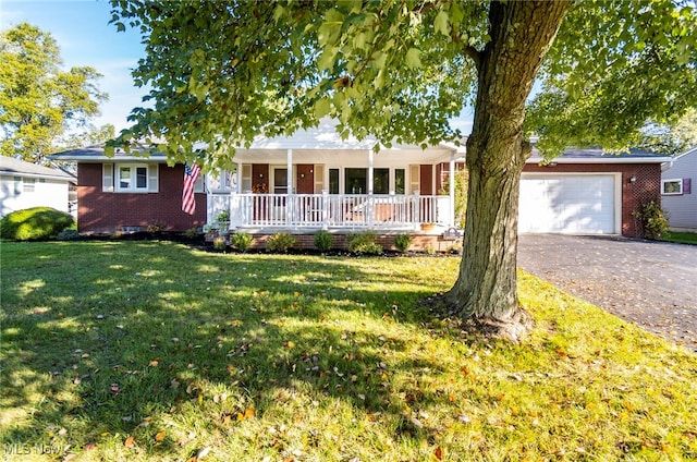 ranch-style house featuring covered porch, a front yard, and a garage