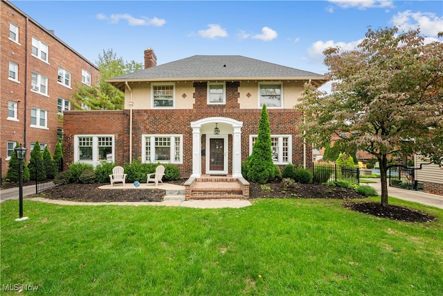 view of front of property featuring brick siding, a chimney, a front yard, and fence