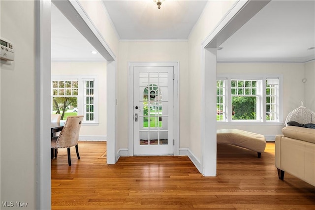 entryway featuring light wood-type flooring, baseboards, a healthy amount of sunlight, and crown molding