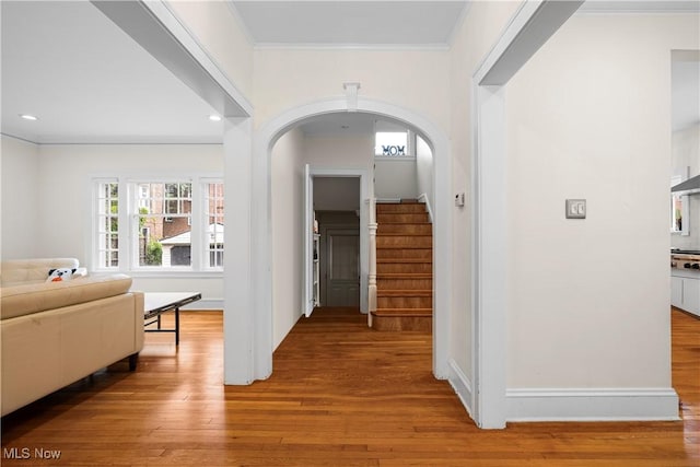 hall with stairs, ornamental molding, recessed lighting, wood finished floors, and arched walkways