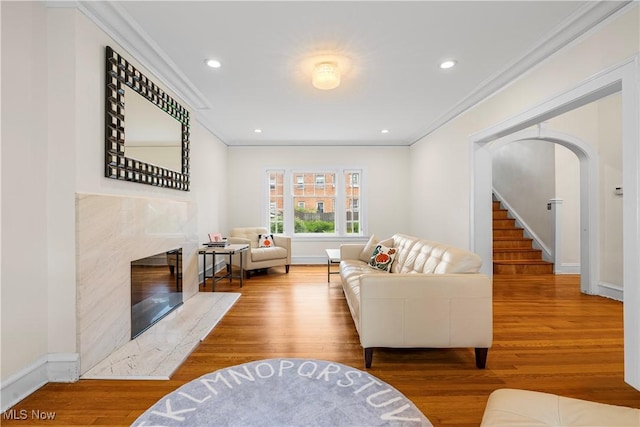 living room with stairway, baseboards, wood finished floors, and crown molding